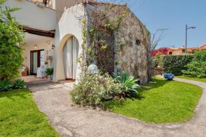 a house with a stone wall and a yard at Il Giardino di Viola in Porto Ottiolu
