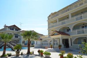a large building with palm trees in front of it at Hotel Villa Basil in Tsilivi