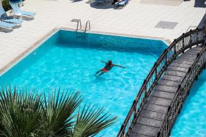 a person swimming in a swimming pool at Hotel Villa Basil in Tsilivi