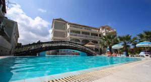 a bridge over a swimming pool in front of a building at Hotel Villa Basil in Tsilivi