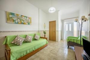 a living room with a green couch and a television at Villas Brites nº2 in Burgau