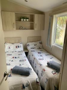 two beds in a small room with a window at Newquay Bay Resort - Sea Breeze 61 in Newquay