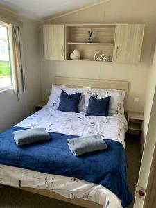 a bedroom with a bed with blue pillows on it at Newquay Bay Resort - Sea Breeze 61 in Newquay