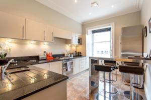 a kitchen with white cabinets and a stainless steel refrigerator at Exclusive 2 Bed, Free Private Parking, in West End in Edinburgh