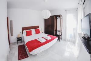 Palacio de Dueñas Private Terrace في إشبيلية: غرفة نوم بسرير كبير ومخدات حمراء وبيضاء
