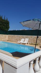 a pool with two chairs and an umbrella at Brisa's Haven Guesthouse !Pet Friendly! in Lagos