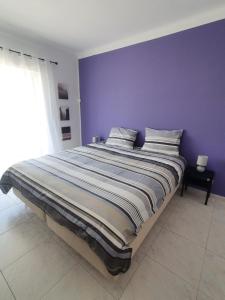 a bedroom with a large bed with a purple wall at Brisa's Haven Guesthouse !Pet Friendly! in Lagos +17 photos