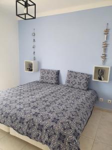 a bedroom with a bed with a blue and white comforter at Brisa's Haven Guesthouse !Pet Friendly! in Lagos