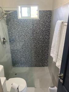 La salle de bains est pourvue d'une douche, de toilettes et d'une fenêtre. dans l'établissement Pine Breeze Apartments, à Bridgetown