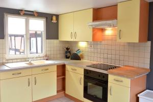 uma cozinha com armários amarelos, um lavatório e um fogão em Gite Géranium*** em Eguisheim