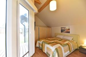 a bedroom with a bed and a large window at Kotedžai GULBĖS TAKAS Šventojoje in Šventoji