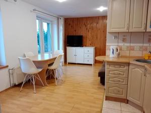 une cuisine avec une table, des chaises blanches, une table et un comptoir dans l'établissement Owocowe Wakacje - Apartament nad jeziorem, à Mikołajki