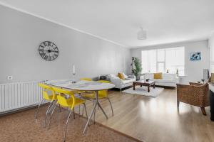 a living room with a table and yellow chairs at Charming, 2 Bedroom Seaside Apartment in Reykjavík