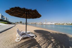 una silla de playa y una sombrilla en la playa en Marbella Luxury 3BR & 5BR Villas at Hayat Island, Mina Al Arab, en Ras al Khaimah