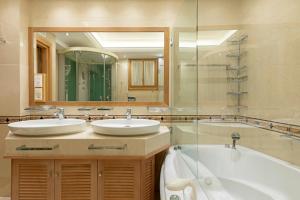 a bathroom with two sinks and a tub and a mirror at Vouliagmeni's Elegance by Acropolis Suites in Athens