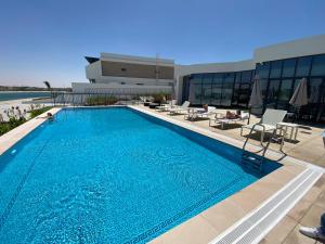 a large swimming pool with chairs and a building at Marbella Luxury 3BR & 5BR Villas at Hayat Island, Mina Al Arab in Ras al Khaimah