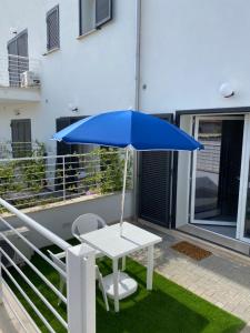 a blue umbrella and a white table and chair on a balcony at Casa Vacanza Surf & Kite Focene in Focene