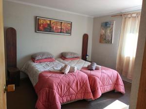 1 dormitorio con 2 camas con mantas y almohadas rosas en Habitaciones en Departamento en Santiago