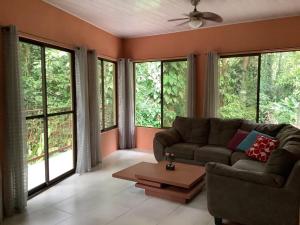 a living room with a couch and large windows at Casa Palmera Cocles, 300m to the beach in Puerto Viejo