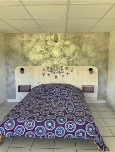 ein Schlafzimmer mit einem Bett mit einer lila Bettdecke in der Unterkunft Chez DouKine in Beure