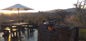 una terraza de madera con mesa y sombrilla en Ifenwenzi bush Chalet, en Buffelspoort