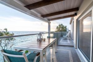 een houten tafel en stoelen op een balkon met uitzicht op de oceaan bij IONIAN BLUE SUITE in Preveza