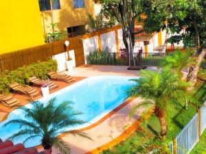 a swimming pool with two palm trees and chairs at Casa de praia com piscina e playground in Vila Velha