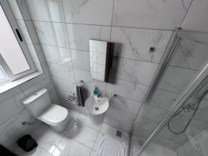 a white bathroom with a toilet and a sink at Zenia Court in Marsaskala