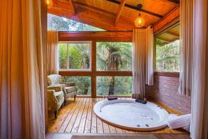 a large bath tub in a room with a large window at Fazenda Hotel Itapuá in Monte Verde