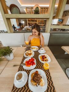 une femme assise à une table avec des assiettes de nourriture dans l'établissement Golf Ville Resort Brisa do Golf -Apartamentos e Cobertura, à Aquiraz