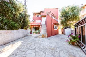dziedziniec w domu z czerwonym budynkiem w obiekcie Helen Corfu House w Korfu