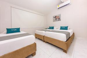 two beds in a room with white walls at Ayenda Isla de Manga in Cartagena de Indias