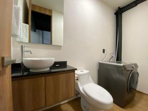a bathroom with a white toilet and a sink at Loft Doble Altura, Colonia Americana @serra in Guadalajara