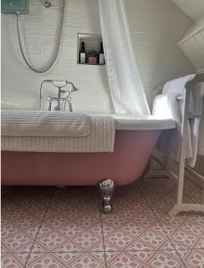 uma banheira na casa de banho com um lavatório em The Pink Cottage (upstairs suite) & Secret Garden em Whitehead