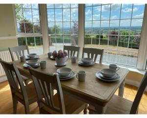 une table en bois avec des chaises et une salle à manger avec une fenêtre dans l'établissement Castleview, Spacious 5 bedroom house with stunning views, à Forkill