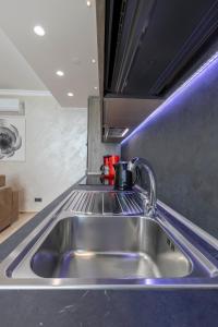 un fregadero de acero inoxidable en una cocina con iluminación púrpura en The Queen Luxury Apartments - Villa Medici, en Luxemburgo