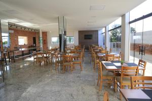 a restaurant with wooden tables and chairs and windows at Pontal Executive Hotel in Curvelo