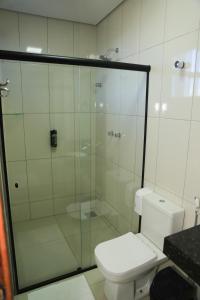 a bathroom with a toilet and a glass shower at Pontal Executive Hotel in Curvelo