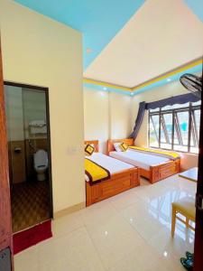 1 dormitorio con 2 camas y baño con aseo en Khách Sạn Nhà Hàng Lương Gia en Ha Giang