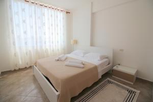 a white bedroom with a bed with towels on it at Skyview Apartments in Sarandë