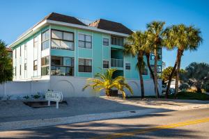 a building with palm trees in front of a street at Beach Potato - 3404 Gulf Dr 5 in Holmes Beach