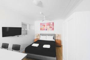 1 Schlafzimmer mit einem schwarzen Bett und 2 Stühlen in der Unterkunft Manly Waves Studios & Apartments in Sydney