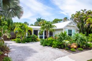 una casa bianca con palme di fronte di Island Time: AMI North End, Pool, Close to City Pier & Pine Ave by Anna Maria Life Vacation Rentals ad Anna Maria