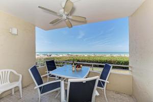 a patio with a table and chairs and a ceiling fan at AMI Dreaming - 4200 Gulf 105 in Holmes Beach