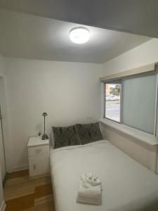 a small bedroom with a white bed and a window at Manly Waves Studios & Apartments in Sydney