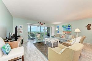 a living room with a couch and a tv at Sunset Beach 102: Gulf Front, Stunning Views, On the Beach, Pool by Anna Maria Life Vacation Rentals in Holmes Beach