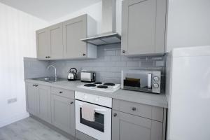 cocina con armarios blancos, fogones y microondas en Platform Stadium apartment with parking, en Hull
