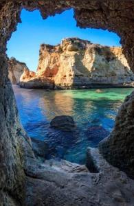 a view of the ocean through a rock cave at Captivating Studio Apartment in Mexilhoeira Grande in Mexilhoeira Grande