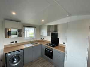a kitchen with a sink and a washer and dryer at Luxury 6 Bed Lodge with Hot Tub in Plymouth