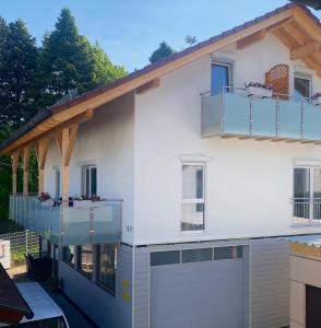 a white house with a balcony and a garage at Ferienwohnungen Auf der Höhe in Engelsbrand